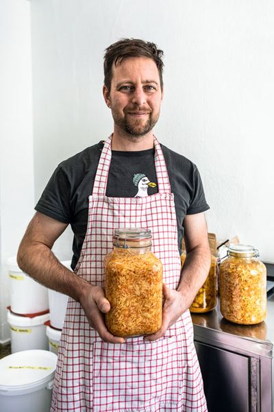 Fabian Czerwinski in Schürze mit einem großen Glas Sauerkraut